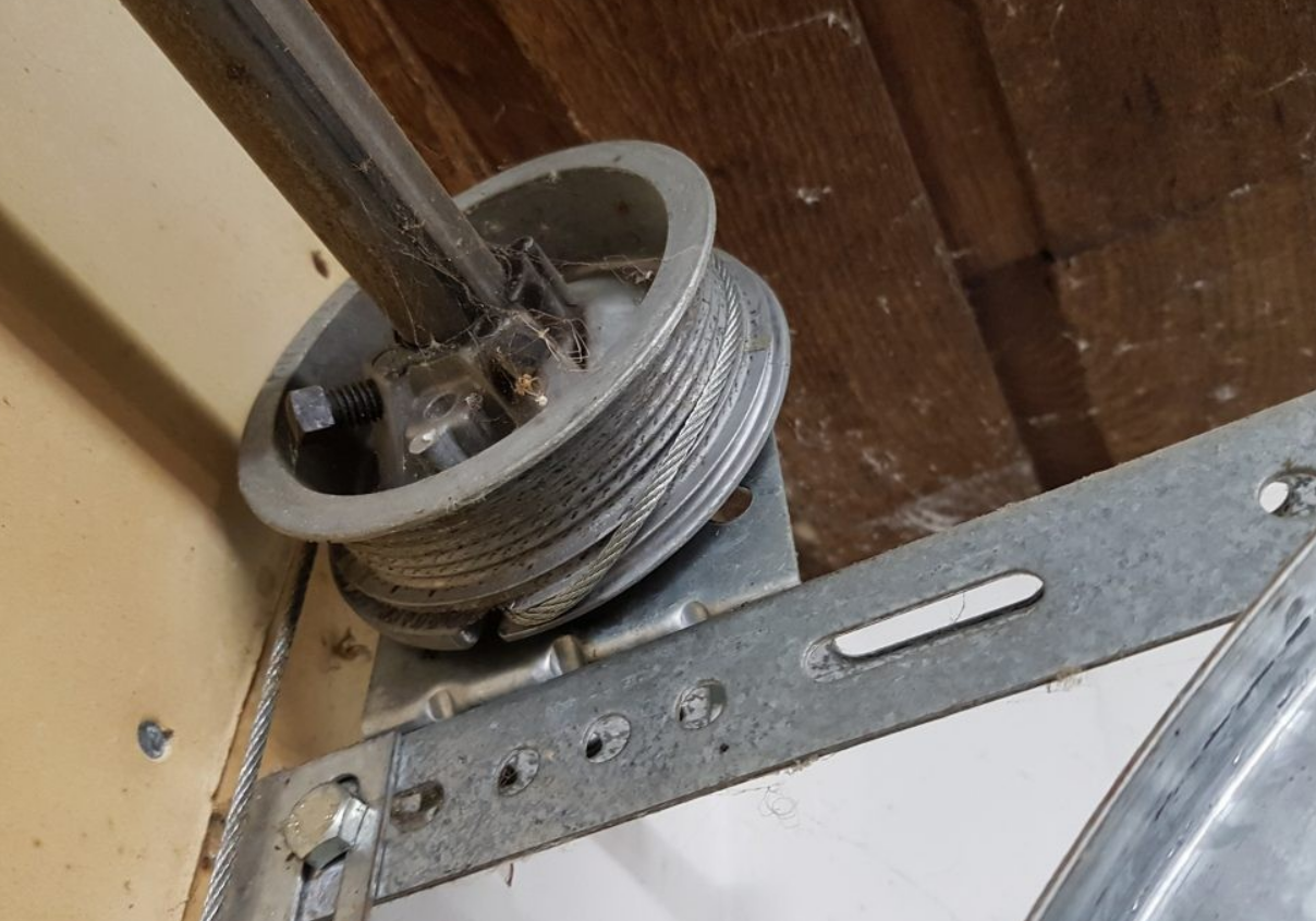 Technician performing garage door cable repair on a residential garage door.