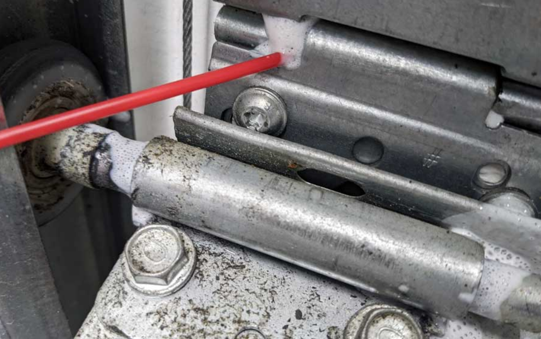 Technician repairing a noisy garage door with tools, showcasing a professional fix for smoother operation