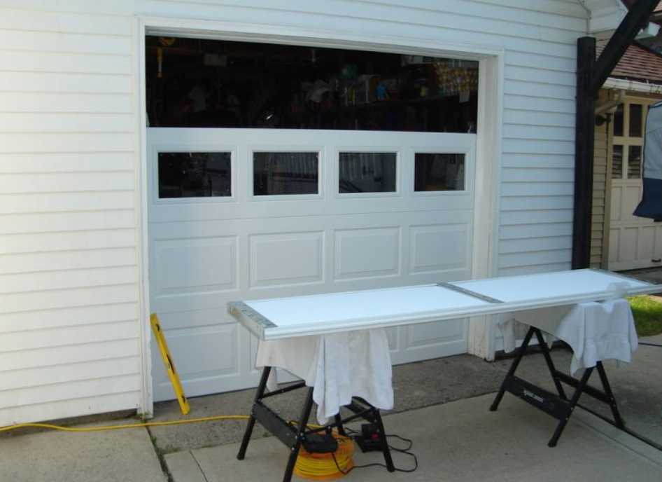 Technician performing a garage door replacement with tools, showcasing professional repair services for a residential garage.