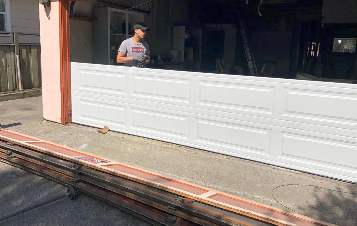 Technician performing a garage door section replacement, ensuring smooth and functional operation of the garage door system